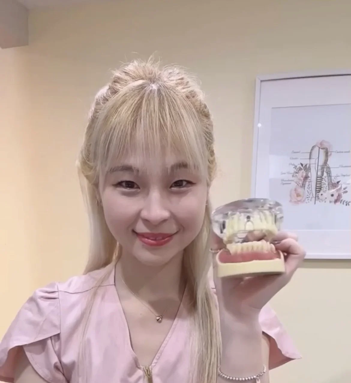 Friendly dental professional holding a tooth model to explain oral health in a dental office.